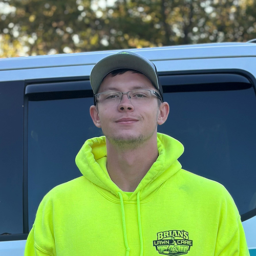 Photo of Brian's Lawn Care employee next to service truck.