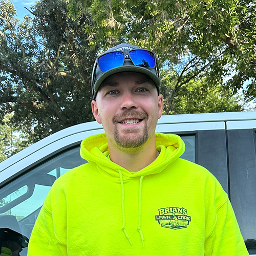 Photo of Brian's Lawn Care employee next to service truck.