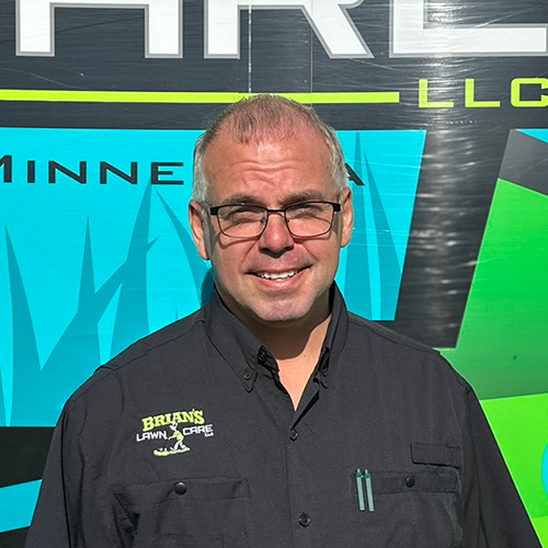 Photo of Brian's Lawn Care employee next to service truck.