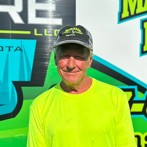 Photo of Brian's Lawn Care employee next to service truck.