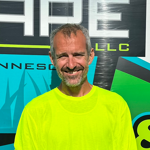 Photo of Brian's Lawn Care employee next to service truck.